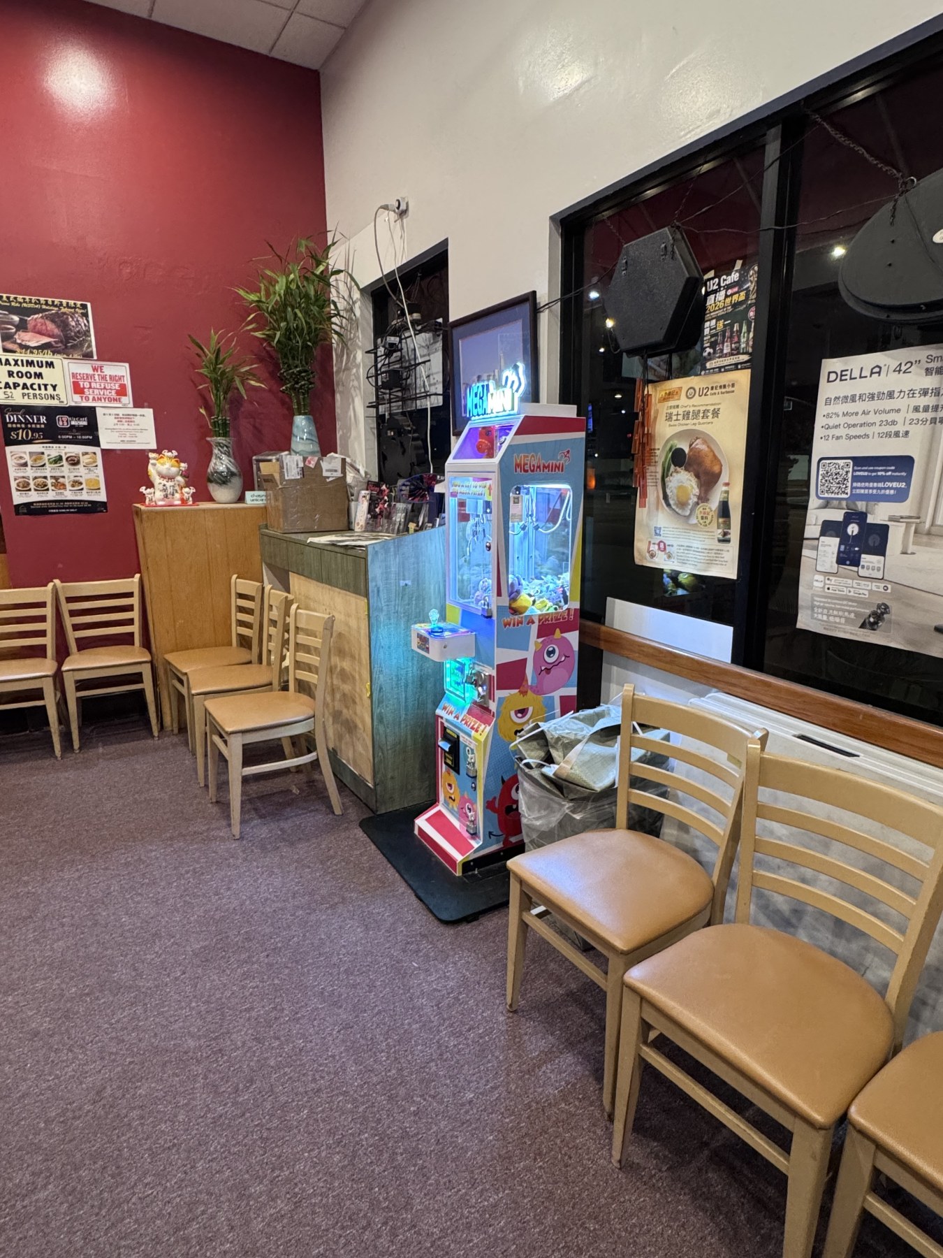 Mega Mini claw machine placed beside chairs inside U2 Cafe and BBQ to show its compact footprint